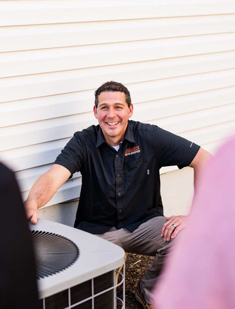 Jonathan in front of air conditioner talking with clients about their inspection